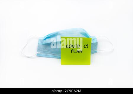 Single use medical face mask with handwritten message on post-it note Covid-19 Plan isolated over white background, coronavirus protection concept Stock Photo