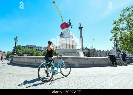 London, UK.  29 July 2020.  Members of the public view artist Heather Phillipson's 'THE END', the newly unveiled Fourth Plinth artwork in Trafalgar Square.  THE END shows a giant swirl of replica whipped cream topped with a cherry, a fly and a drone.  Its drone transmits a live feed of the square which can be watched on a dedicated website.  The installation, originally planned for 26 March 2020 but postponed due to the coronavirus pandemic, will remain on display for the next year two years.  Credit: Stephen Chung / Alamy Live News Stock Photo