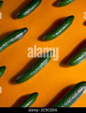 Pattern of fresh cucumbers on orange surface Stock Photo