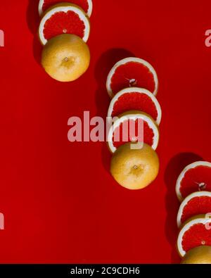 Pattern of sliced grapefruit on red surface Stock Photo