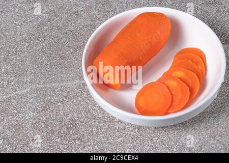 Boiled carrots, sliced in circles on a white plate. Stock Photo