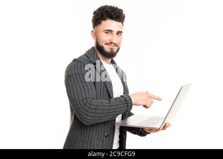 Working with joy. Handsome young man using his laptop and looking at camera with smile while standing against white background Stock Photo