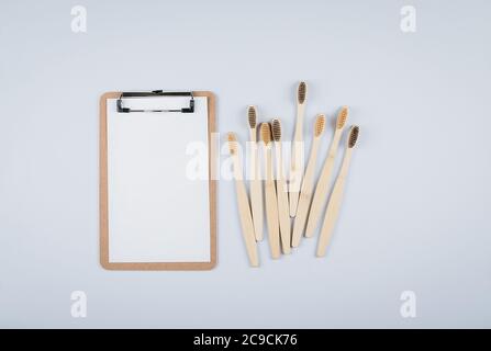 Flat lay composition with bamboo toothbrushes and empty white notepad blank for text on grey background. Eco natural bamboo toothbrushes. Zero waste, Stock Photo