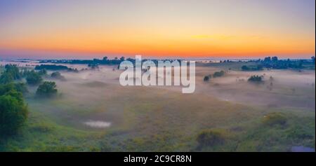 Panorama of a summer wet meadow after a rain with swamps along the river during sunset Stock Photo