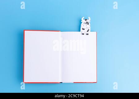 open red book with cow bookmarks on blue background, copy space. top view, blank Stock Photo