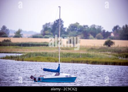 28 July 2020, Mecklenburg-Western Pomerania, Fährdorf: A small sailboat lies in the Wismar Bay next to the bridge to the Baltic Sea island Poel. Photo: Jens Büttner/dpa-Zentralbild/ZB Stock Photo