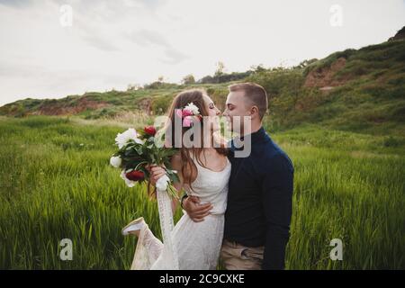 Outdoor wedding ceremony, stylish happy smiling groom and bride are hugging and looking at each other. The moment before kiss Stock Photo