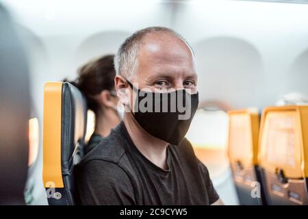 Man wearing protective mask sitting in the airplane Stock Photo