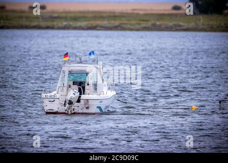 28 July 2020, Mecklenburg-Western Pomerania, Fährdorf: A small motorboat lies in the Wismar Bay next to the bridge to the Baltic Sea island Poel. Photo: Jens Büttner/dpa-Zentralbild/ZB Stock Photo