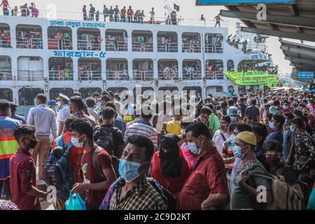 Muslim Bangladeshi homebound people are seen wearing facemasks while they gather at Sadarghat launch terminal to travel to their villages ahead of the Eid festival in Dhaka. Millions of city dwellers travel to their villages to celebrate Eid during the Coronavirus pandemic. Stock Photo