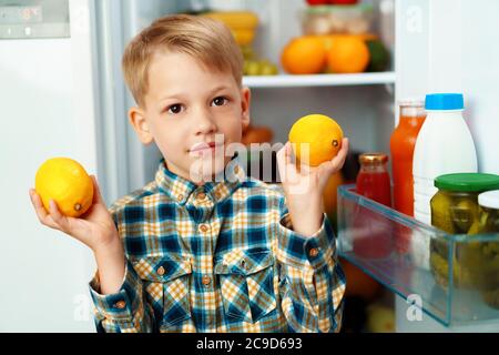 Little boy standing in front of open fridge and choosing food Stock Photo