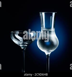 Strong alcoholic drink in frozen glass with ice. Frozen glasses on a dark blue background. Stock Photo