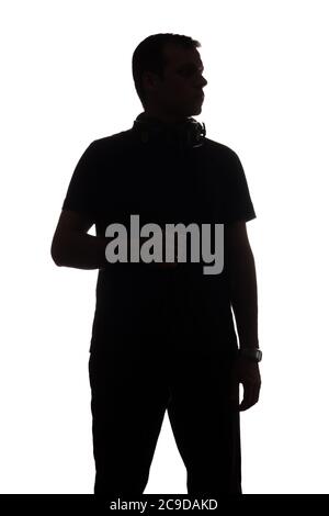 Silhouette of young man with a smartphone listening to music with big headphones old on shoulders Stock Photo