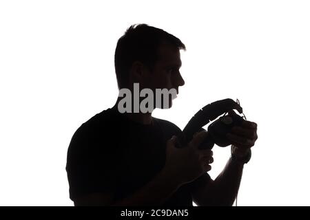 Silhouette of young man with a smartphone listening to music with big headphones old Stock Photo