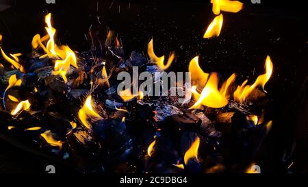 Hot coals in the fire.actively smoldering embers of fire.Burning firewood in the fireplace close up, BBQ fire.black burned charcoal Stock Photo