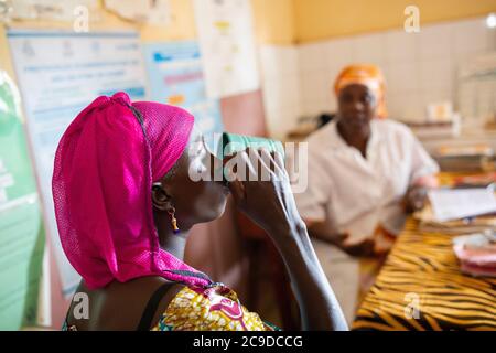 A nurse distributes malaria prophylaxis specialized for pregnant women to a female patient at a health center in Kouroussa, Guinea, West Africa. Stock Photo