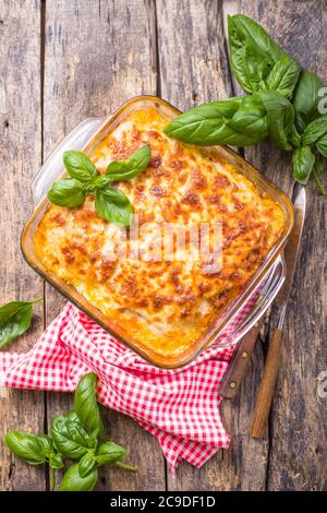 Traditional italian lasagna with vegetables, basil, minced beef meat, tomato and cheese on wooden  background. Stock Photo