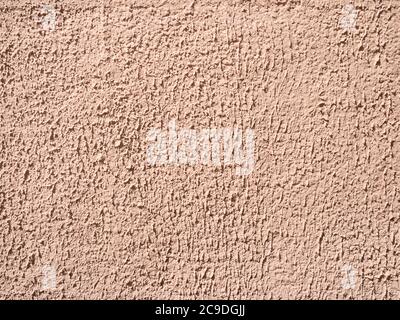 brown painted surface of coarse plastered outdoor wall lit by sun in sunny day Stock Photo