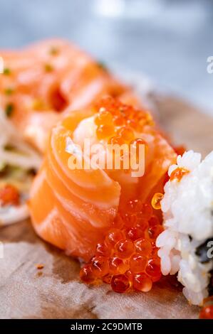 Japanese food, fresh sushi or sashimi made from rice with salmon, avocado, cucumber, red fish caviar, tempura shrimps close up Stock Photo