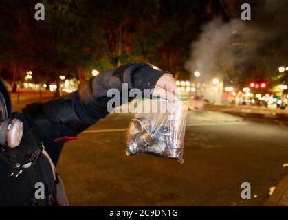 Portland, Oregon, USA. 30th July, 2020. Portland Protest: July 30 .A Protestor holds up a bag of Tear gas canisters and munitions launched at her and other protestors in one round of attacks by Federal Agents in unmarked military uniforms, on the night it was announced they are withdrawing from Portland. Credit: Amy Katz/ZUMA Wire/Alamy Live News Stock Photo