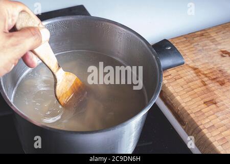 Mixing together ingredients of hot-water crust pastry dough, using wooden  spoon Stock Photo - Alamy