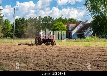 Otsego, Michigan - A 90-year-old farmer drives a Farmall Model M tractor, disking a field on a small farm in western Michigan. International Harvester Stock Photo