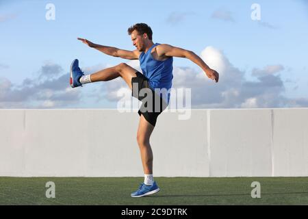Runner man getting ready to run doing warm-up dynamic leg stretch exercises routine, Male athlete stretching lower body hamstring muscles before going Stock Photo
