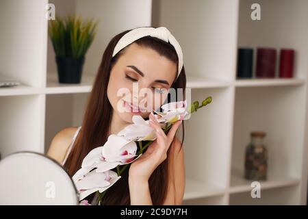 Attractive young woman in bathroom after shower is standing in front of mirror with face cream. Women care. Stock Photo