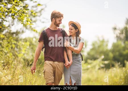 Outdoor activities. Young Caucasian couple walk marked route through national park. One day radial hike in summer. Two tourists with backpacks guy and Stock Photo