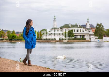Woman walking in city park relaxing on weekend. Person enjoying lake view in Copenhagen, Denmark. Spring lifestyle activity, people outside. Stock Photo