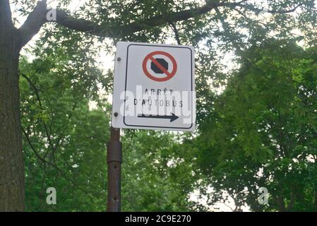 No stop sign says a bus stop in French with a blurry background of tree branches and leaves Stock Photo