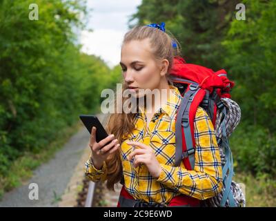 Female hiker looking at her mobile phone. Woman trekker taking help of mobile phone for navigation in forest. Lost in forest and using GPS app in mobi Stock Photo