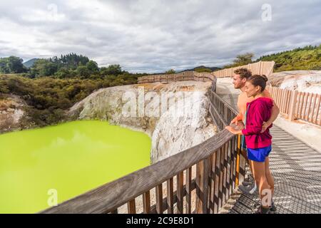 New Zealand travel tourists looking at green pond. Tourist couple enjoying famous attraction on North Island, geothermal pools at Waiotapu, Rotorua. Stock Photo