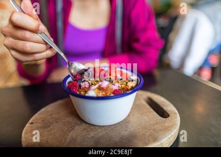 Acai bowl woman eating morning breakfast at cafe. Closeup of fruit smoothie healthy diet for weight loss with berries and oatmeal. Organic raw vegan Stock Photo