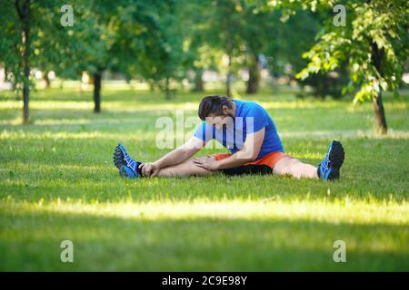 Man stretches outdoor in summer time. The concept of an active lifestyle and healthy lifestyle in age after 40. Stock Photo