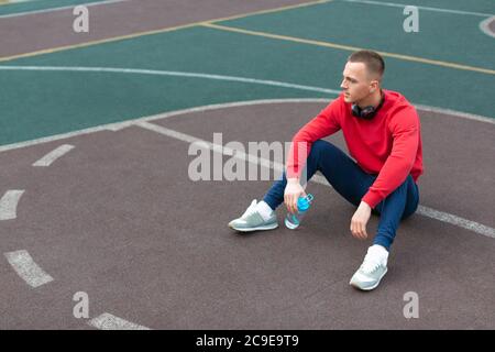 Man having rest after training on the sports ground. Sport and healthy lifestyle concept. Stock Photo