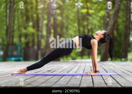 Female trainer in sportswear, practicing yoga asanas, doing the reverse plank Stock Photo