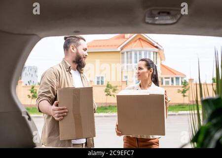 Young couple holding cardboard boxes and loading car truck while leaving house Stock Photo