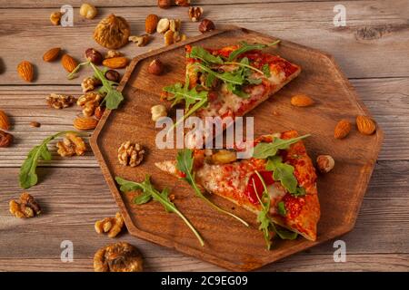 close up image of  vegetarian cheese and tomato pizza decorated with fresh arugula leaves and grilled egg plants slices. It is served on wooden tray w Stock Photo