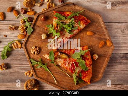 Flat lay close up image of  vegetarian cheese and tomato pizza decorated with fresh arugula leaves and grilled egg plants slices. It is served on wood Stock Photo