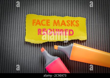 FACE MASKS REQUIRED concept. Text on torn, colored paper on corrugated background Stock Photo