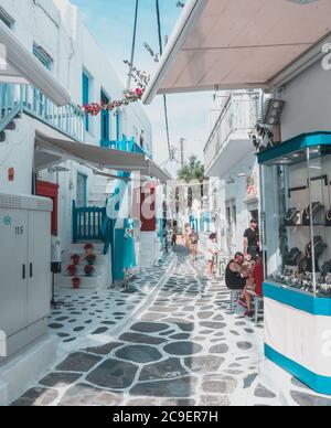 Colorful houses and commerce on blue and white colors with flowers in the old town of Mykonos Island, Greece. Stock Photo