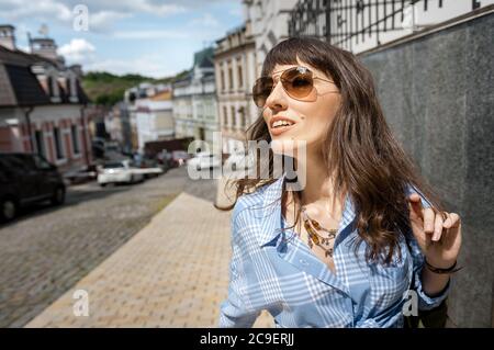 girl in a blue shirt and jeans. He walks through the city with a backpack and looks away. A woman travels alone, walks in an unfamiliar city Stock Photo