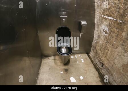 Toilet bowl in a public toilet surrounded by metal walls Stock Photo