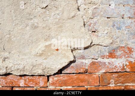 Empty old brick wall texture. Shabby facade of a building with damaged plaster. Stock Photo