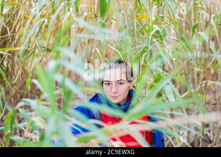 Young woman hiding behind a bush in the woods Stock Photo