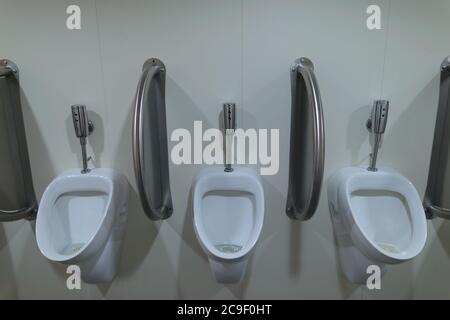 Three ceramic urinals inside the men's public toilet