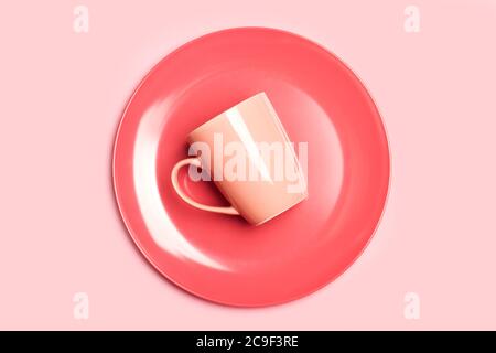 A pink mug on a pink plate and on a pink background in a top view Stock Photo