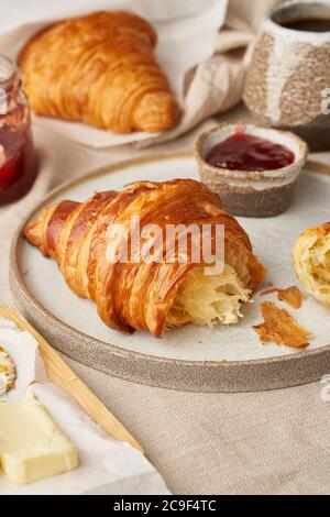 Two delicious croissants on plate and hot drink in mug, side view, vertical Stock Photo