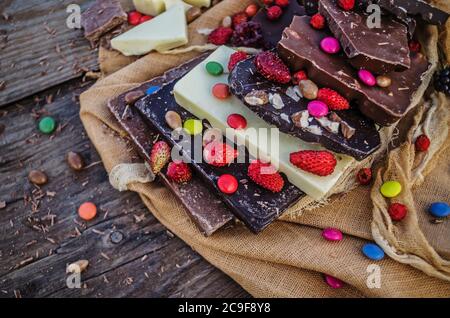 Chocolate  mix  with  nuts and  dried fruits on rustic wooden background. Chocolate blocks stack with different kind of chocolate. Chocolate bar piece Stock Photo